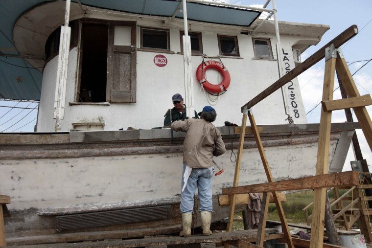 These fishermen work on a friend's oyster boat as it sits in a dry dock due to the ruined oyster beds, on the first anniversary of the Deepwater Horizon oil spill.  Even as somber remembrances marked the first anniversary of the worst offshore oil...
