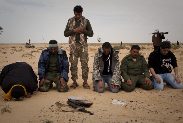 Libyan rebels pray in the desert.