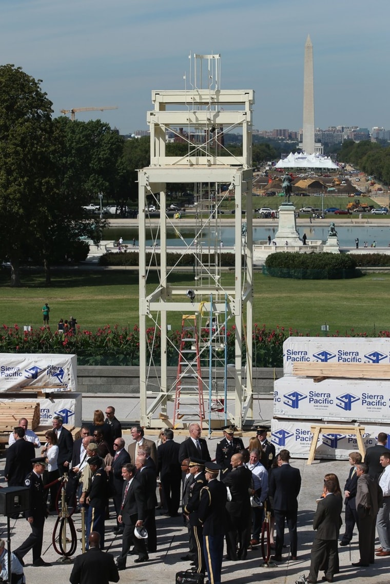 Officials and members of the news media gather at the base of the center camera platform during the \"First Nail\" ceremony, signifying the start of construction of the 2013 Inaugural Platform on the West Front of the U.S. Captiol September 20, 2012, in...