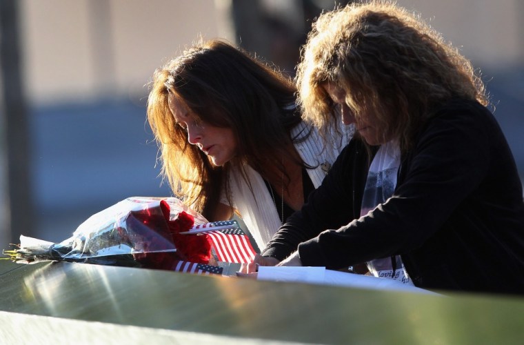 Tina Grazioso, left, looks at the name of her husband, John Grazioso, who died in the 9/11 terrorist attacks on the World Trade Center, during the 11th anniversary observance of the attacks at the World Trade Center Memorial in New York. At right is...