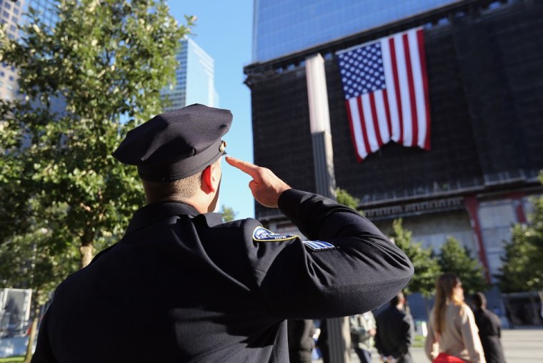 A New York City policeman salutes a flag hanging from One World Trade ceremonies for the 11th anniversary of the terrorist attacks on lower Manhattan at the World Trade Center on September 11, 2012, in New York City.