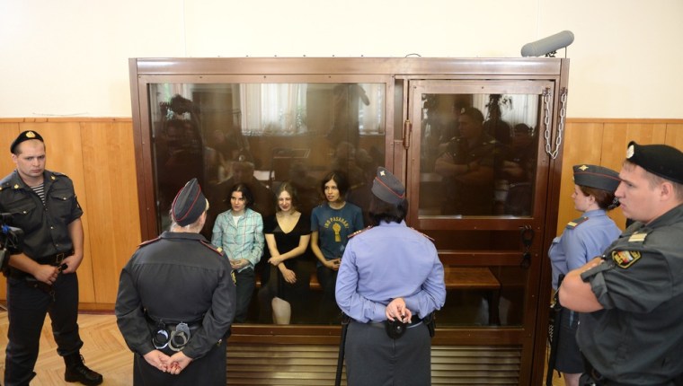 Members of the all-girl punk band \"Pussy Riot\" Yekaterina Samutsevich (L), Maria Alyokhina (C) and Nadezhda Tolokonnikova (R) sit in a glass-walled cage during a court hearing in Moscow on Agust 17, 2012.