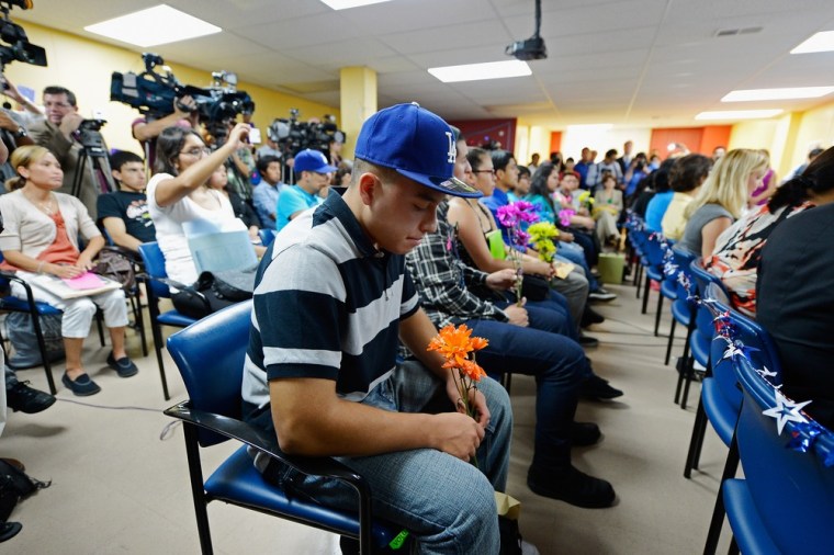 Osbaldo Perez along with a group of immigrants, known as DREAMers, hold flowers as they listen to a news conference to kick off a new program called  Deferred Action for Childhood Arrivals at the Coalition for Humane Immigrant Rights of Los Angeles.