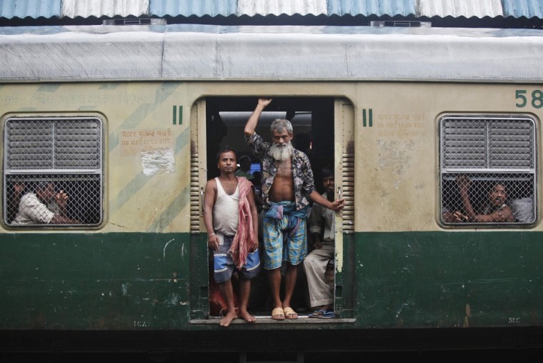 Passengers stand at the doorway of a train as they wait for the electricity to be restored at a railway station in Kolkata July 31.