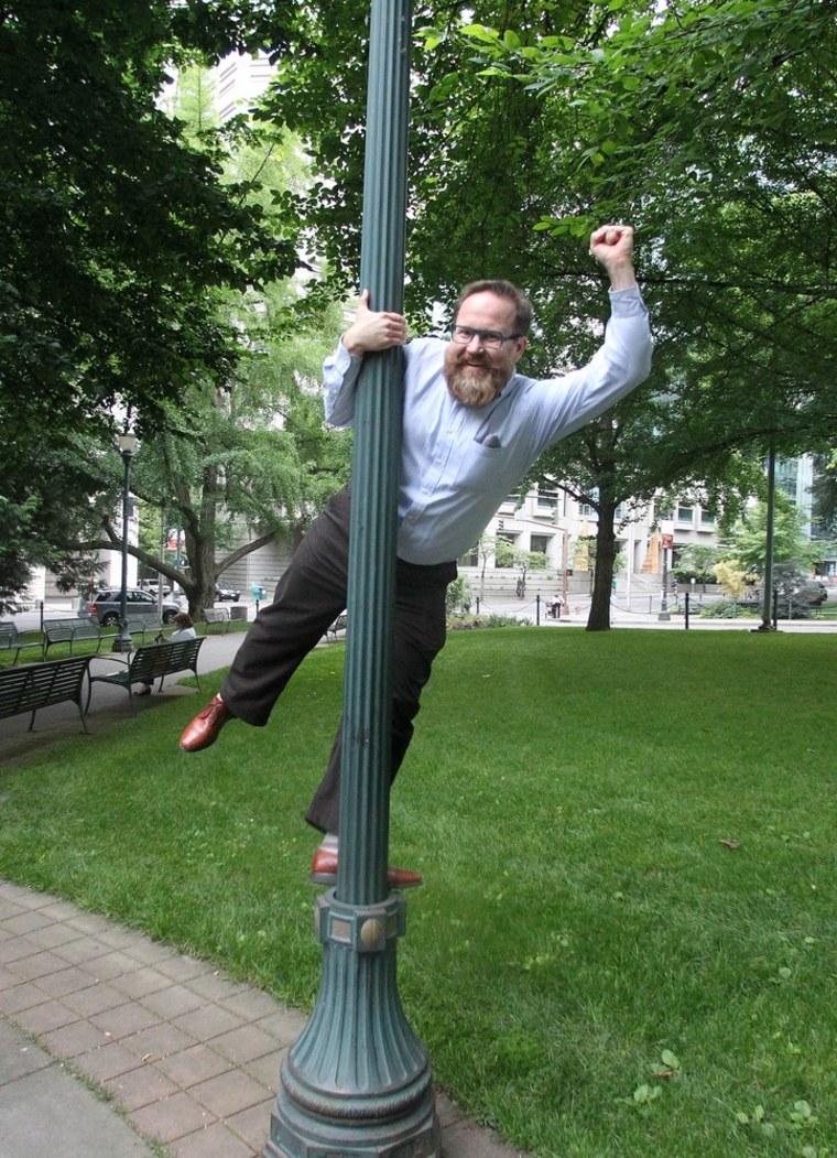 John Brennan, the man who stripped at Portland International Airport to protest TSA screeners, celebrates by swinging on a light post outside the Multnomah County Courthouse following his trial Wednesday, July 18 in Portland, Ore.