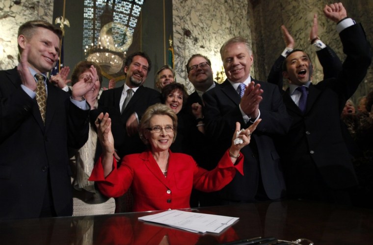 Washington Gov. Christine Gregoire, seated, raises her arms as legislators and supporters cheer behind her after she signed into law a measure that legalizes same-sex marriage Monday, Feb. 13, 2012, in Olympia, Wash.
