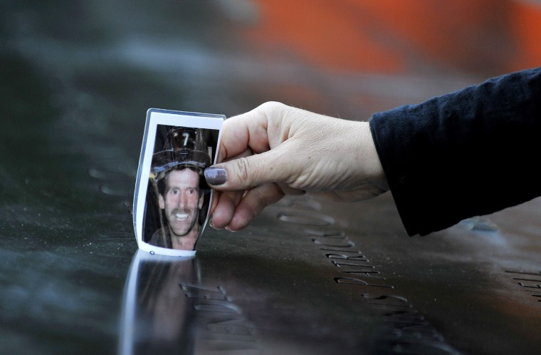 Christine Gonda places a picture of firefighter George Kane in the engraving of his name at the South Pool during memorial ceremonies for the eleventh anniversary of the terrorist attacks on lower Manhattan at the World Trade Center site September 11,...