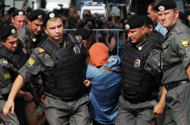 Russian riot policemen detain a supporter of all-girl punk band \"Pussy Riot\" near a court building in Moscow on Agust 17, 2012.