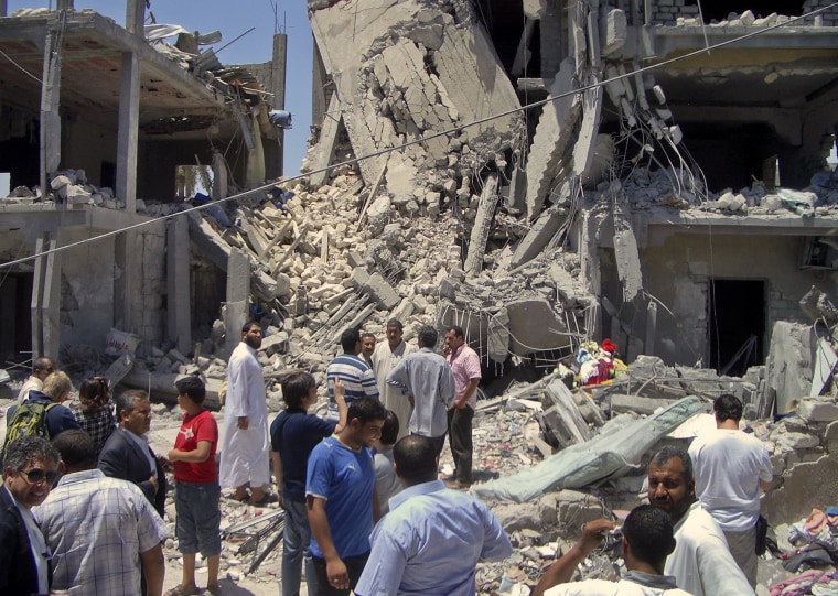 In this photo taken on a government-organized tour, members of the media and others examine the remains of a damaged residential building in Tripoli, Libya Sunday, June 19, 2011. The Libyan government accused NATO of bombing a residential neighborhood...