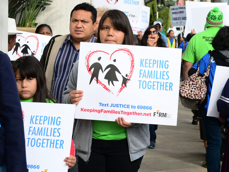 Immigrant families and supporters of their cause hold banners and shout slogans while marching in front of Senator Dianne Feinstein's office on March 4, 2013 in Los Angeles, California, at the launch of a caravan tour called \"Our Golden Promise -...