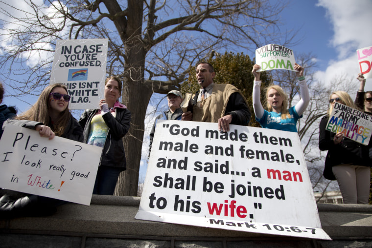 Allan Hoyle of North Carolina, with the large white sign, center, speaks out against gay marriage across from the street from the Supreme Court in Washington, Wednesday, March 27, 2013, after the court heard arguments on the Defense of Marriage Act ...