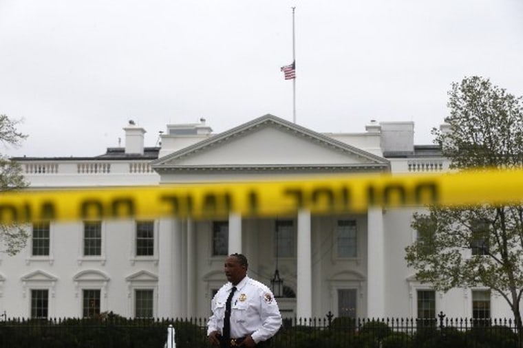 A Uniformed Division Secret Service officer stands guard behind police tape on Pennsylvania Avenue, which is closed to pedestrians, in front of the White House in Washington, Tuesday, April 16, 2013, with the American flag is seen at half staff above...