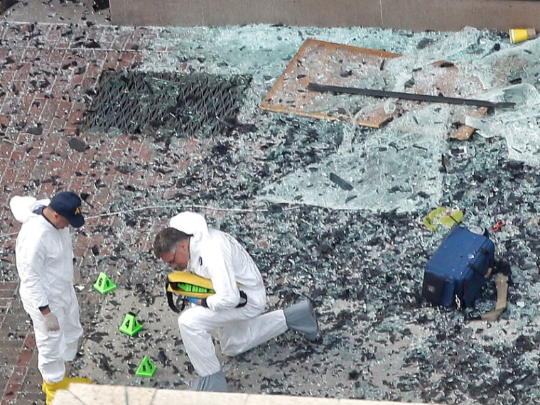 Two men in hazardous materials suits put numbers on the shattered glass and debris as they investigate the scene at the first bombing on Boylston Street in Boston Tuesday, April 16, 2013 near the finish line of the 2013 Boston Marathon, a day after two...