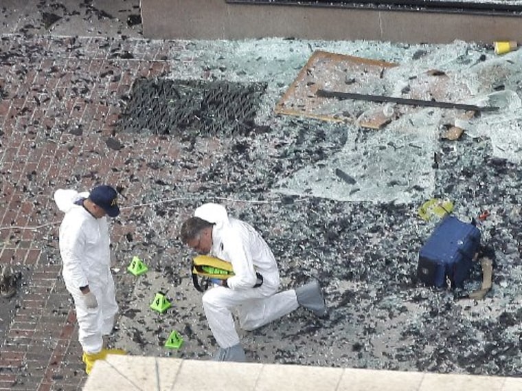 Two men in hazardous materials suits put numbers on the shattered glass and debris as they investigate the scene at the first bombing on Boylston Street in Boston Tuesday, April 16, 2013, near the finish line of the 2013 Boston Marathon, a day after...