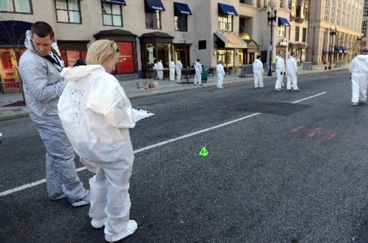 FBI crime scene investigators stand near an evidence marker on Boylston Street just past Berkeley Street as they sweep up towards the bomb scene of the Boston Marathon April 17, 2013 in Boston, Massachusetts. (Photo by Darren McCollester/Getty Images)