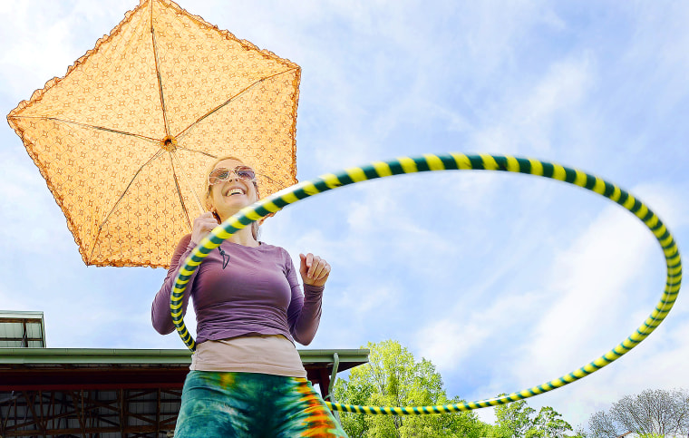 Amy Laura Hall hoola-hoops holding her parasol, during the  Durham's Earth Day Festival, in Durham Central Park, Durham N.C., Sunday, April 21, 2013. (AP Photo/The Herald-Sun, Bernard Thomas)