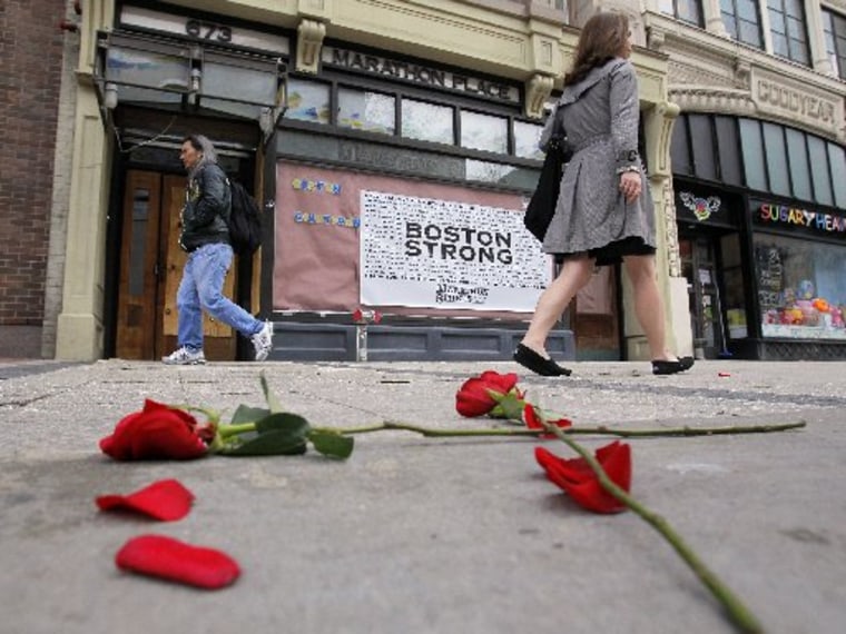 Flowers lay on the sidewalk at the site of the first explosion as people walk along Boylston Street after the street reopened to the public for the first time since the Boston Marathon bombings in Boston, Massachusetts April 24, 2013. REUTERS/Jessica...