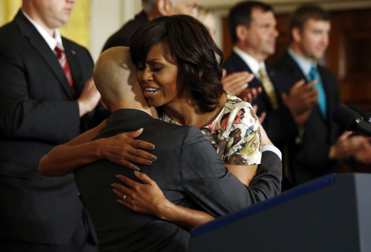 U.S. first lady Michelle Obama hugs U.S. Navy veteran David Padilla, who has found employment with a transport company after leaving military service, during an event in the East Room of the White House in Washington, April 30, 2013. Obama announced...