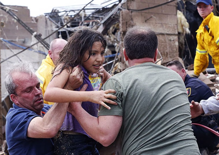 A child is pulled from the rubble of the Plaza Towers Elementary School in Moore, Okla., and passed along to rescuers Monday, May 20, 2013. A tornado as much as a mile (1.6 kilometers) wide with winds up to 200 mph (320 kph) roared through the Oklahoma...