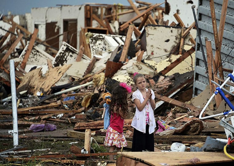 Two girls stand in rubble after a tornado struck Moore, Oklahoma, May 20, 2013. A 2-mile-wide (3-km-wide) tornado tore through the Oklahoma City suburb of Moore on Monday, killing at least 51 people while destroying entire tracts of homes, piling cars...