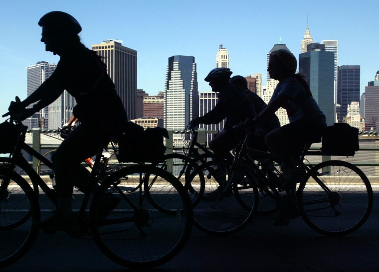 Some of the estimated thirty thousand participants in the 25th annual Bike New York tour pass by a view of the lower Manhattan skyline, in the Brooklyn borough of New York, Sunday, May 5, 2002. Roads are closed down to allow bicyclists to travel the 42...