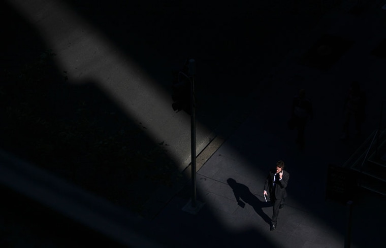 A man talks on his mobile phone as he walks through a shaft of sunlight along a street in Sydney's central business district (CBD) April 18, 2013. (Photo by David Gray/Reuters)