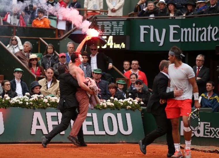 Rafael Nadal of Spain looks on as security guards restrain a protester after he lit a flare and ran on court before the start of a game in the Men&#039;s Singles final match between Rafael Nadal of Spain and David Ferrer of Spain on June 9, 2013 in...