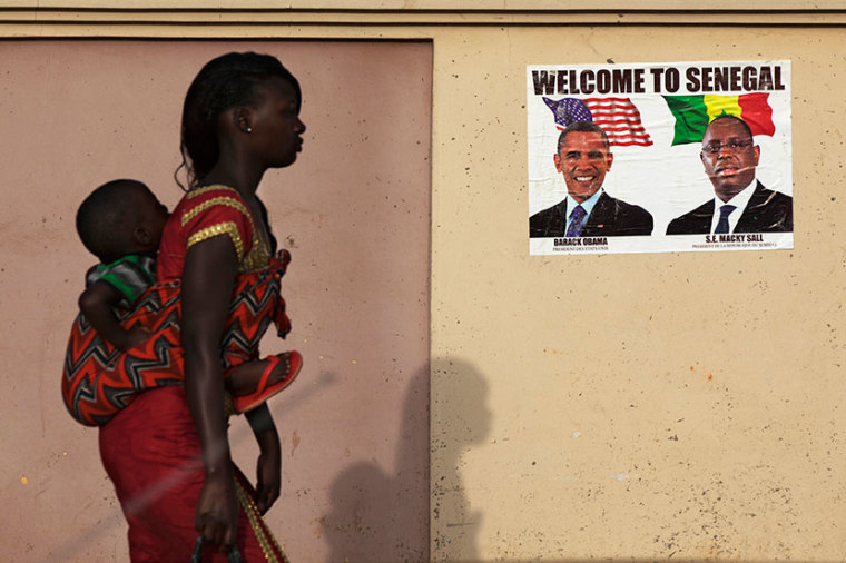 A woman carrying her baby on her back walks past a poster of U.S. President Barack Obama and Senegal's President Macky Sall before Obama's visit in Dakar June 26, 2013.  (Photo by Joe Penney/Reuters)