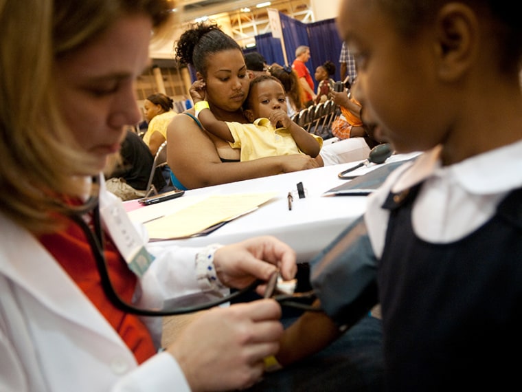 Avanna Parent of New Orleans, LA, holds her two year-old son Leo as Dr. Kim Davis (L) takes a blood pressure test on her five year-old daughter Paige (R) at the New Orleans Communities Are Responding Everyday (C.A.R.E.) Clinic, at the Ernest N. Morial...