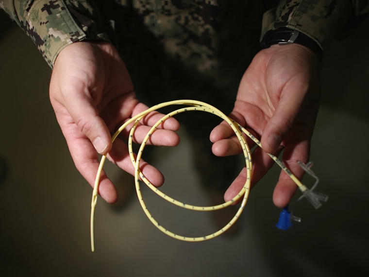 A military doctor holds a feeding tube used to feed detainees on hunger strike at the detainee hospital in Camp Delta which is part of the U.S. military prison for 'enemy combatants' on June 26, 2013, in Guantanamo Bay, Cuba. (Photo by Joe Raedle/Getty...