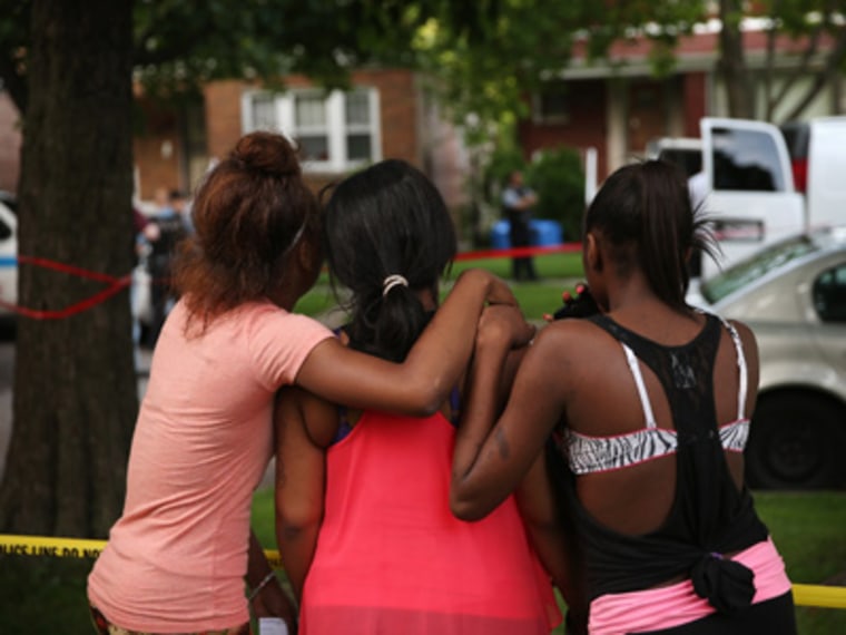 Young women watch as police prepare to remove the remains of their friend after he was shot and killed on June 22, 2013 in Chicago, Illinois. (Photo by Scott Olson/Getty Images)