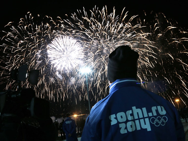 A volunteer watches fireworks during a ceremony to mark a 1 year to the start of 2014 Winter Olympics, in Sochi, Russia, on Thursday, Feb. 7, 2013. (Photo by Ivan Sekretarev/AP)