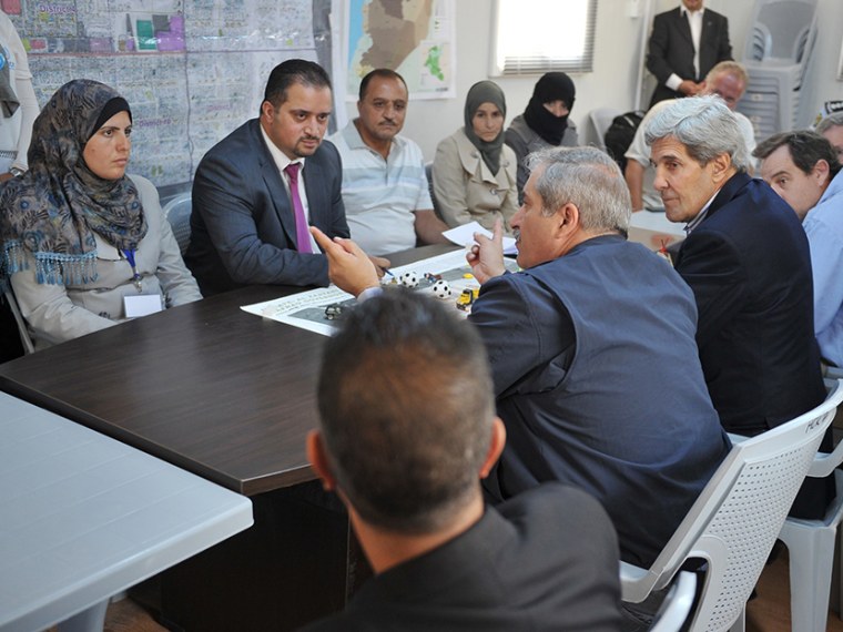 US Secretary of State John Kerry (C-R) and his Jordanian counterpart Nasser Judeh (C) meet with Syrian refugees at the Zaatari refugee camp near the Jordanian city of Mafraq on July 18, 2013.  (Photo by Mandel Ngan/AFP/Getty Images/Pool)