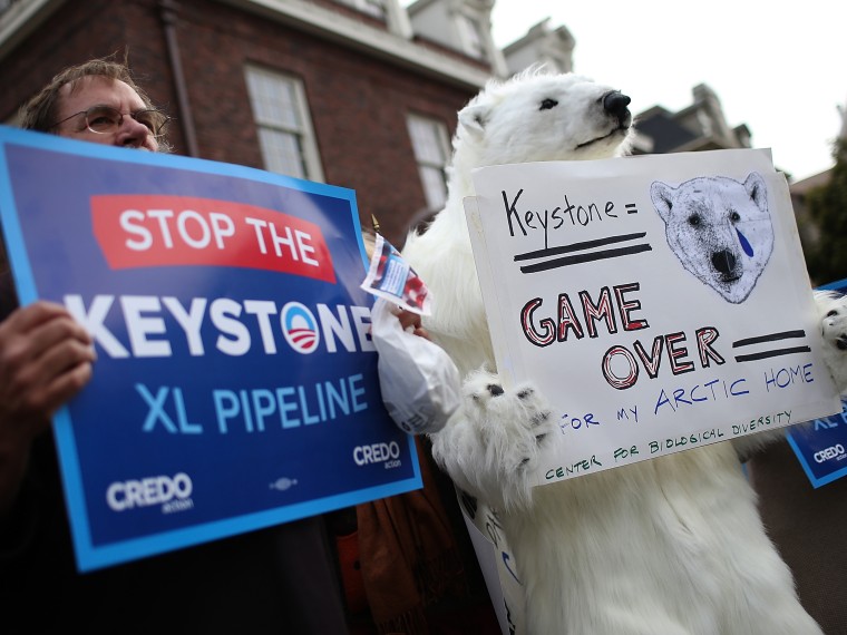 Demonstrators hold signs as they protest near the site of a fundraiser on April 3, 2013 in San Francisco, California.  Hundreds of protesters staged a demonstration against war and the Keystone XL pipeline outside of a fundraiser to be attended by U.S....