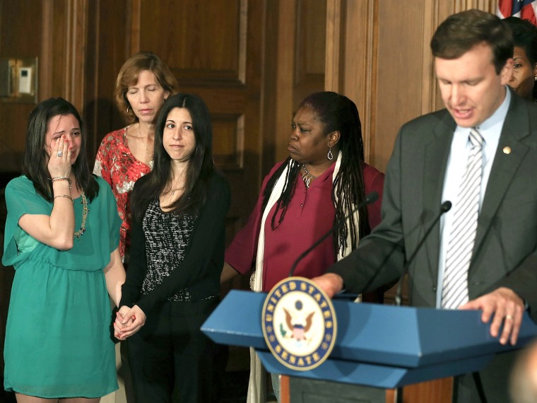 Jillian Soto (L), who lost her sister in the Newtown shooting, holds hands with Miya Rahamim, who lost her father in a unrelated shooting, as they listen to Sen. Chris Murphy, a Connecticut Democrat, read names of shooting victims during a news...