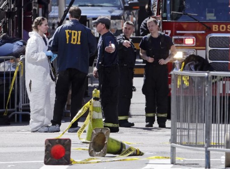 Boston firefighters, right, talk with FBI agents and a crime scene photographer Tuesday, April 16, 2013,  at the scene of Monday's Boston Marathon explosions. (AP Photo/Charles Krupa)