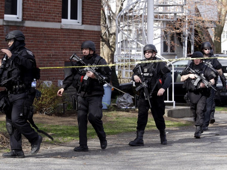 Officials wearing tactical gear search an apartment building in Watertown, Mass., Friday, April 19, 2013.  Two suspects in the Boston Marathon bombing killed an MIT police officer, injured a transit officer in a firefight and threw explosive devices at...