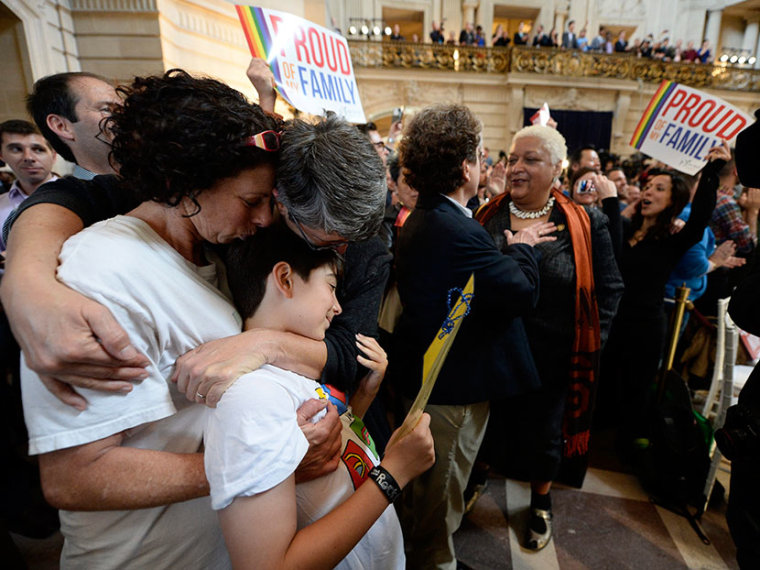 Sue Rochman (L) and her partner Robin Romdalvik of San Francisco, (third L) kiss their eight-year-old son, Maddox (second L), as they listen to the Supreme Court rulings on California's Prop 8 ban on same-sex marriages as well as on the Defense of...