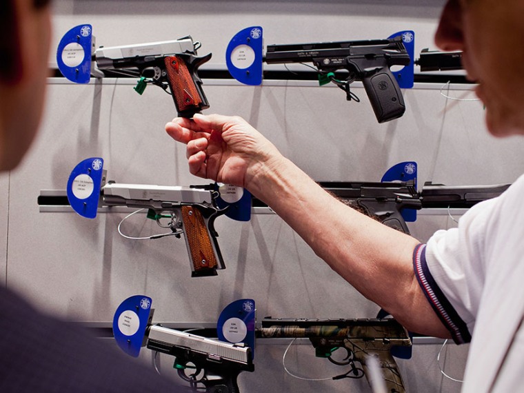 Visitors look at a Smith &amp; Wesson display during the NRA Annual Meetings and Exhibits April 14, 2012 at America's Center in St. Louis, Missouri. (Photo by Whitney Curtis/Getty)