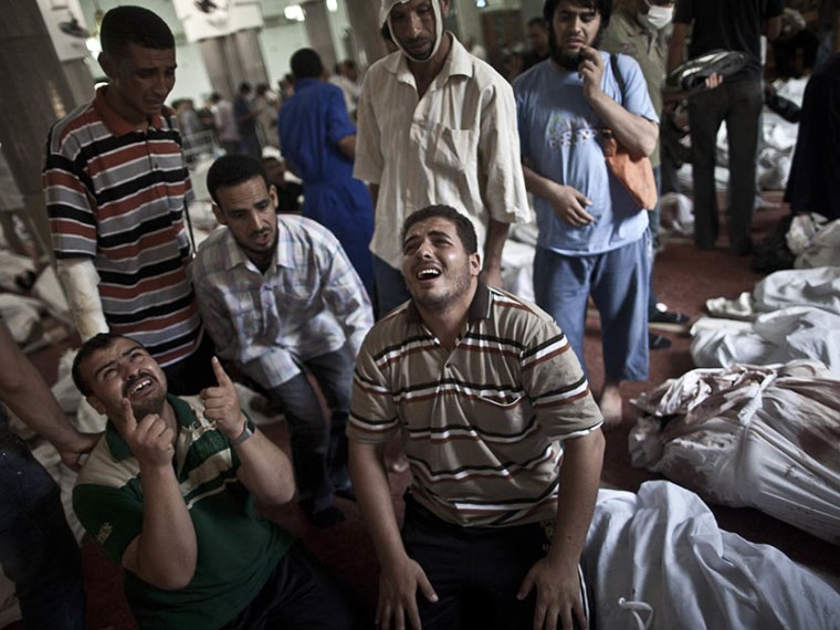 Egyptians mourn at a mosque in Cairo where lines of bodies wrapped in shrouds are laid out on August 15, 2013, following a crackdown on the protest camps of supporters of ousted Islamist president Mohamed Morsi the previous day. (Photo by Mahmoud...