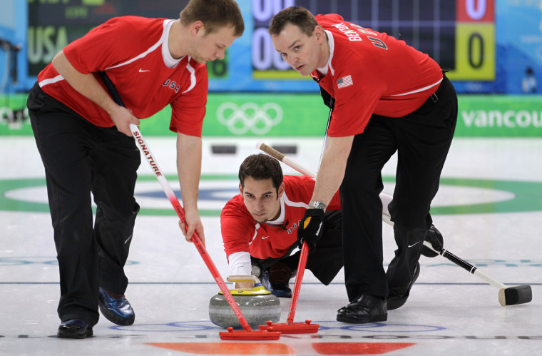 America's Jason Smith, center, delivers the stone for sweepers, Jeff Isaacson, left, and Jason Smith in men's curling at the Vancouver 2010 Olympics in...