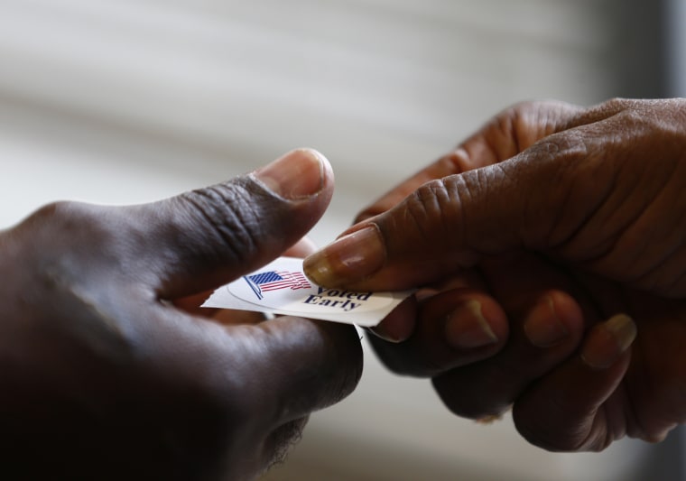 A poll worker hands a sticker to a voter at a polling place in Charlotte, NY.