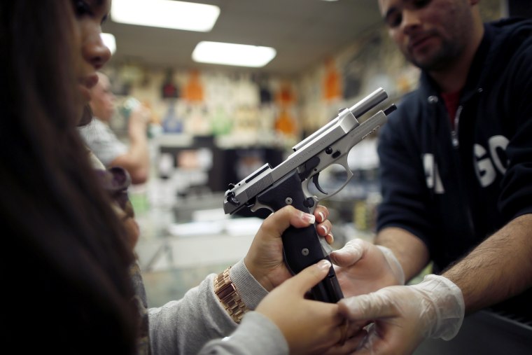 Range safety officer Luis Pena, 23, (R) demonstrates gun safety to Faith Herradura, 23, at the Los Angeles gun club in Los Angeles, on January 23, 2013.