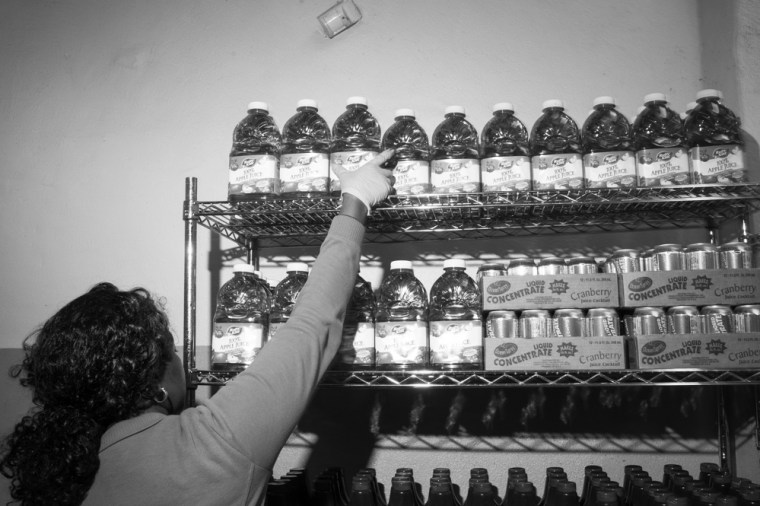 Janet Major puts cranberry juice onto a shelf while helping people fulfill their food allotments.