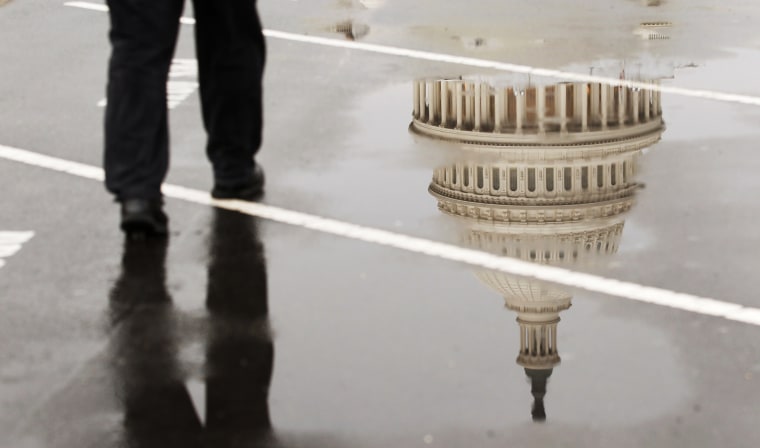 The dome of the U.S. Capitol Building is reflected in a puddle on a rainy morning in Washington.