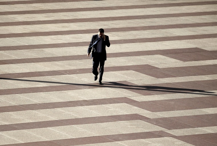 A man talks on his cell phone as he walks in the financial district in Madrid, Tuesday, Oct. 29, 2013.
