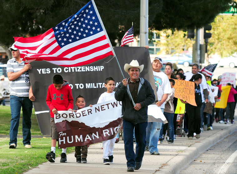 Jose Gonzalez of El Paso, Texas, center, carries the American flag as he leads Azriel Gutierrez, 11, left, Christian Flores, 3, Emiliano Cardona, 11, and hundreds of fellow marchers along Picacho Avenue in Las Cruces, N.M. on October 5, 2013 as they rally