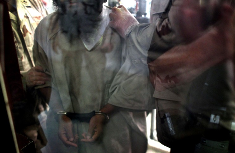 U.S. military guards move a detainee inside the detention center for \"enemy combatants\" on Sept. 15, 2010 in Guantanamo Bay, Cuba.