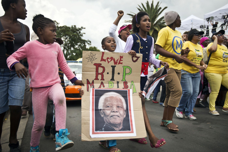 A young girl marches with others to celebrate Nelson Mandela's life, in the street outside his old house in Soweto, Johannesburg, South Africa, Dec. 6, 2013.