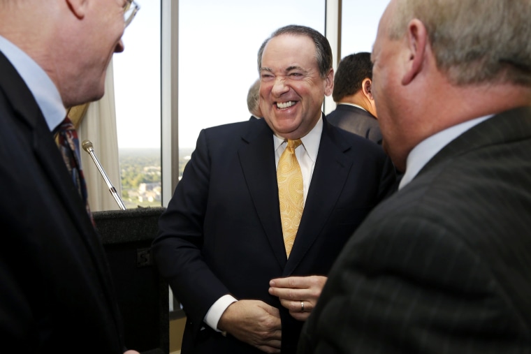 Former Arkansas Gov. Mike Huckabee laughs as he is greeted after a meeting of the Political Animals Club in Little Rock, Ark., Oct. 25, 2013.